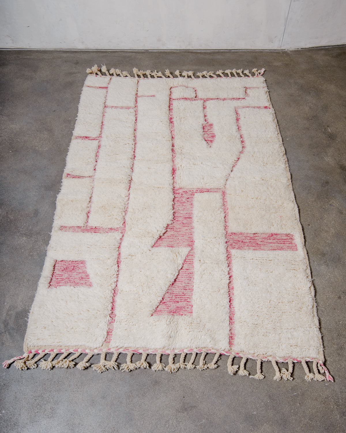 Berberlin Beniourain rug in cream and pink wool laying flat on a concrete floor.